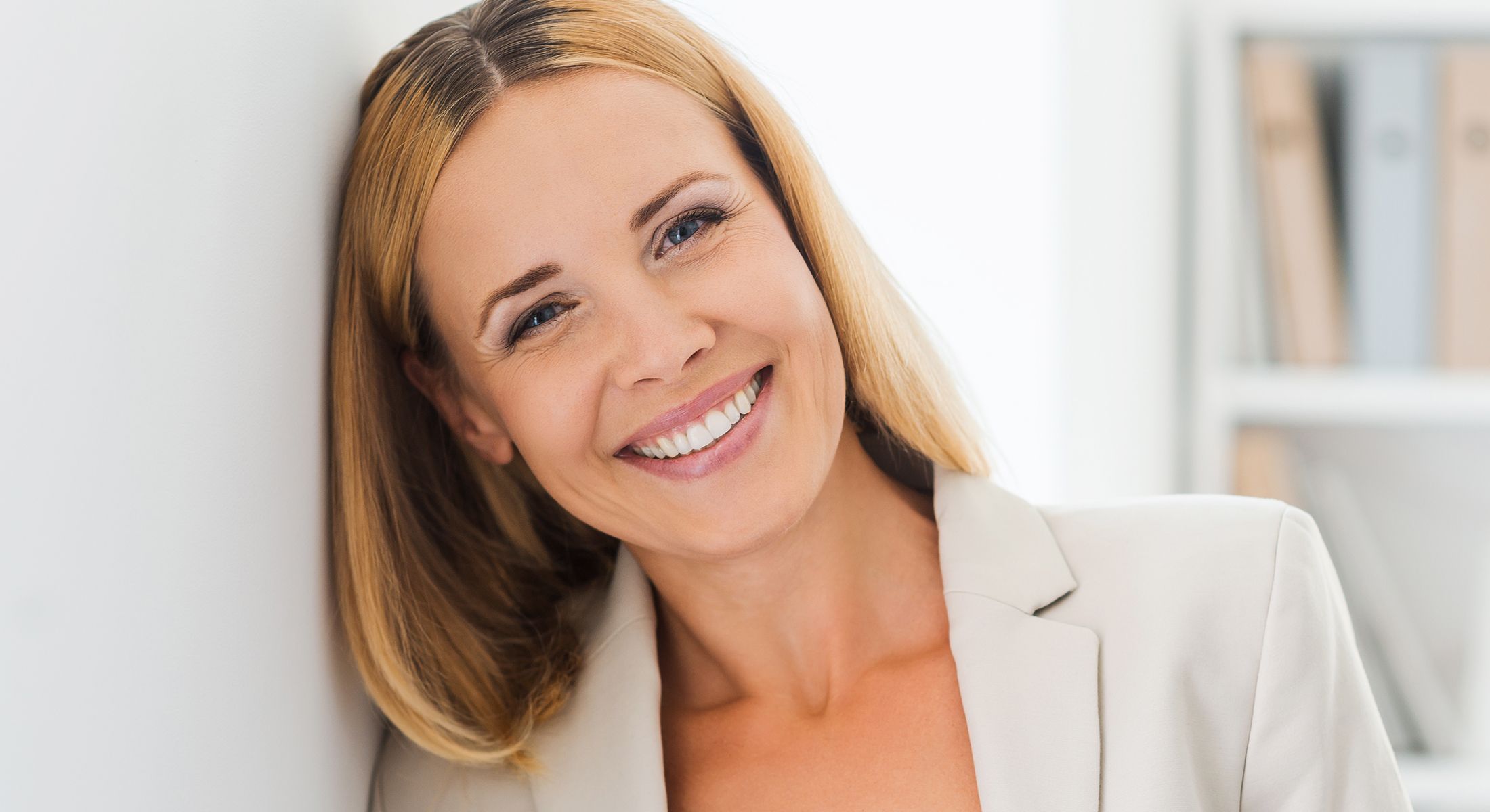 Smiling woman with blonde hair in office setting.