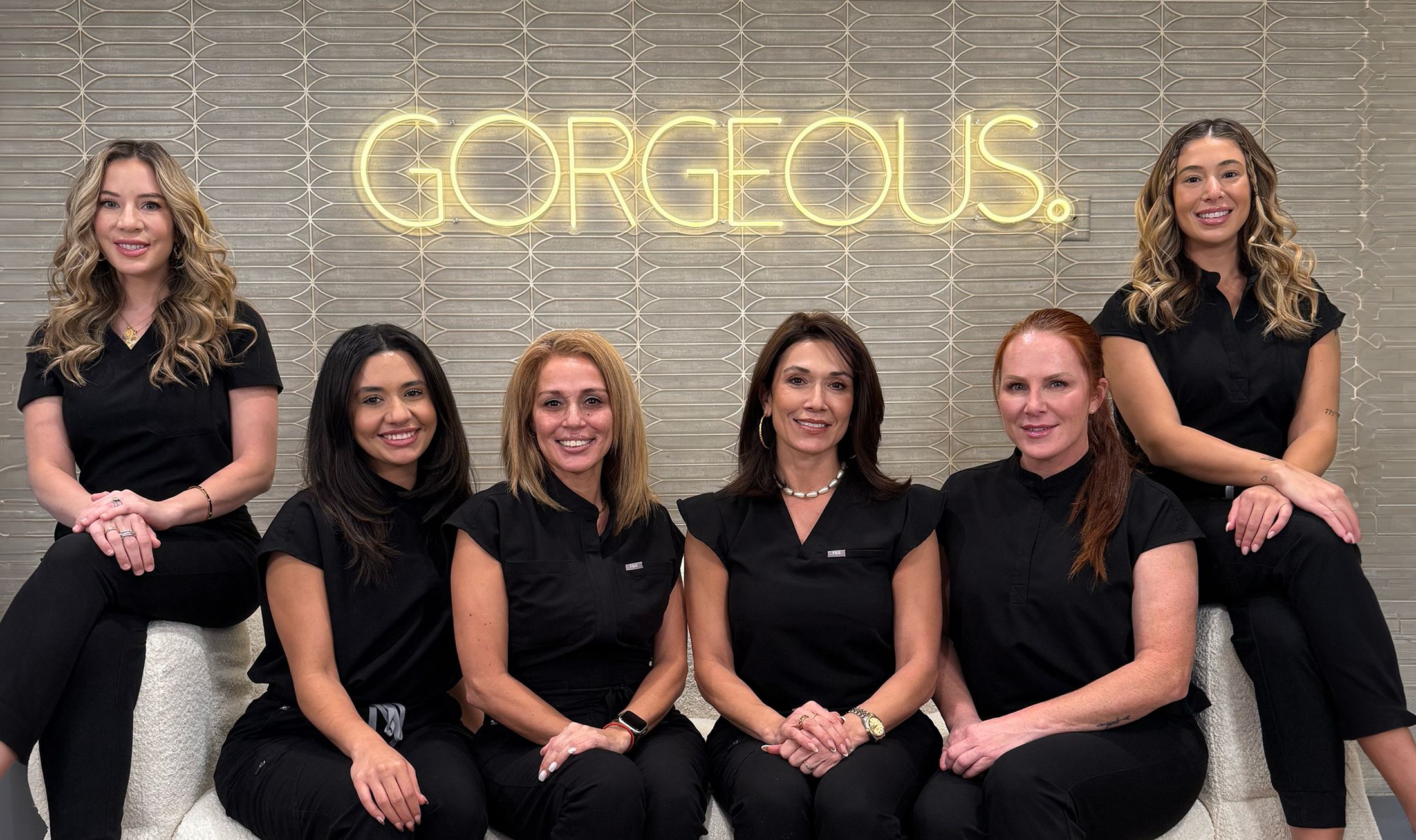 Group of women in black outfits smiling together.
